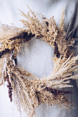 Stylish autumn wreath. Hands holding dry grass, wildflowers and wheat rustic wreath