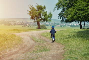 Obraz premium Happy kid boy of 6 years having fun in autumn park with a bicycle on beautiful fall day. Active child wearing bike helmet