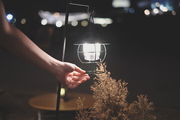 Hand holding a n old lamp, oil lamp or lantern. concept of camping at inght time or campfire...