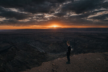 Fototapeta na wymiar Kleiner Junge schaut in den Fish River Canyon bei Sonnenuntergang (Hobas, Namibia)