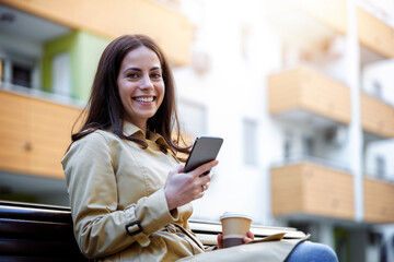 Woman sitting on bench and using smart phone