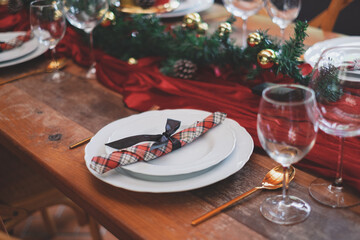A Close up a plates set up for Christmas table setting and set up for traditional lunch or dinner on a wooden table with, tableware and decorations with wine glass. Concept of Christmas preparing.