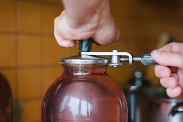 Hands closing the lid on a jar while preserving cherry compote. Homemade preparations for the winter. Canning