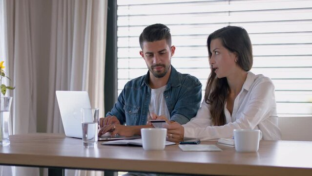Young couple at home, using laptop for planning of finances.