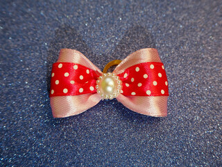 a pink bow with polka dots for dogs lies on a blue shiny background top view.  accessories for dogs.  decorations