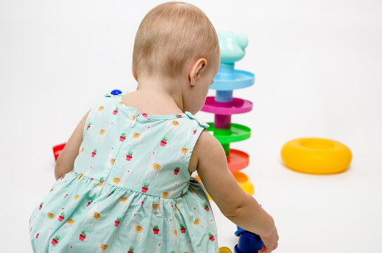 Little Child Playing With Colorful Toys On White Background Photo From The Back.