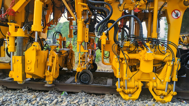 Plasser India or also called Tamping Machine functions to compact the stones under the rail tracks bearings. Yellow railway Motor Grader machine on working.