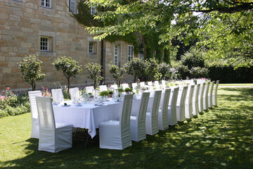 Feierlich weiß eingedeckter Tisch für eine Hochzeit in einer historischen Parklandschaft 