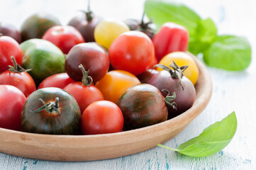 Bunte Tomaten in einer Holzschale und Basilikum
