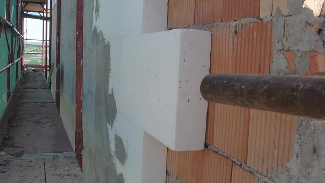 Scaffolding around the building. POV from above scaffolding. Reconstruction of old building. Putting thermal insulation - polystyrene on the building wall