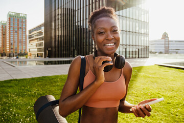 Young beautiful happy fit afro woman with phone and headphones