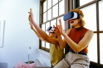 Fototapeta premium Female couple wearing VR headsets