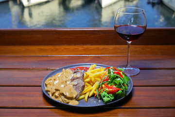 beef chop steak with salad , fried potatoes and mustard sauce in dish. Food and Vegetable concept. Restaurant and menu theme. With Red Wine.