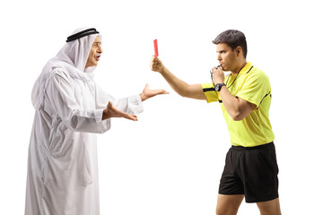 Profile shot of a football referee blowing a whistle and showing a red card to an angry arab man