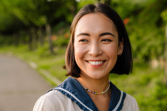 Young smiling asian woman walking in park