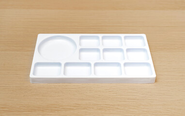 White watercolor palette. Empty watercolor tray isolated on wood background. White palette.