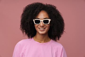 Portrait of young beautiful smiling curly woman in sun glasses