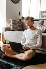 Young handsome smiling happy redhead man working with laptop