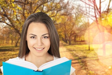 Fototapeta premium Happy young beautiful woman reading book on autumn background