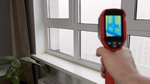 Inspection of a window block inside the room with a thermal imager, searching for heat loss in a building. Thermography concept