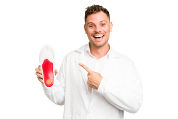 Young caucasian chiropodist man isolated smiling and pointing aside, showing something at blank space.