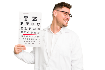 Young caucasian oculist man isolated looks aside smiling, cheerful and pleasant.