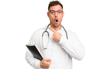 Young doctor caucasian man holding a book isolated pointing to the side
