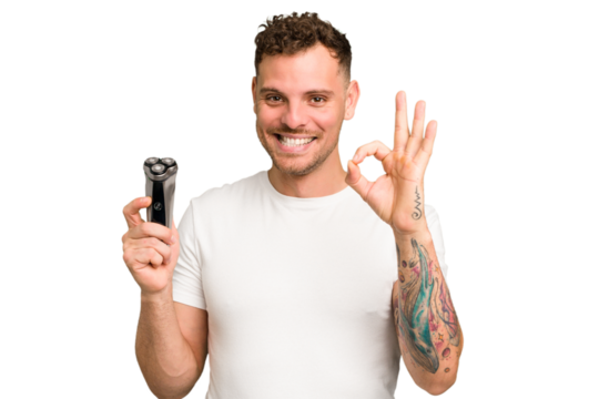 Young caucasian man holding a razor isolated cheerful and confident showing ok gesture.