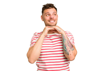 Young caucasian handsome man isolated keeps hands under chin, is looking happily aside.