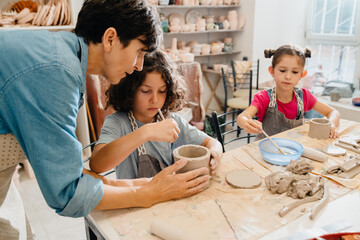 Female teacher working with group of kids in pottery workshop