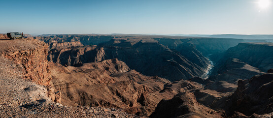 Eine einzelne nicht erkennbare Touristin sitzt auf der Motorhaube ihres 4WD am Rande des Fish River...