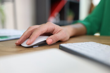 Close-up of woman's hand resting on modern wireless computer mouse.