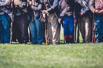 Veterans with guns standing in a row in a field reenacting the American Civil War.