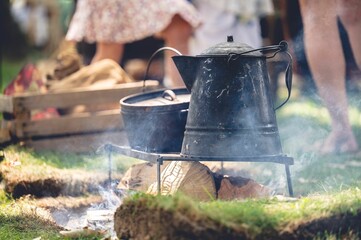 Old metal cooking pots on smoking wooden logs during the American Civil War reenactment event.