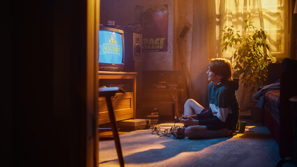 Young Boy Playing Eighties Eight Bit Arcade Video Game on a Console at Home in His Room with...