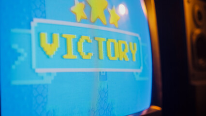 Close Up Footage of a Retro TV Screen with an Eight Bit Eighties Inspired Console Arcade Video Game. Victory Word Displayed on Vintage Television Set Connected to Gaming Station.