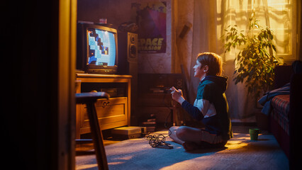 Young Boy Playing Eighties Eight Bit Arcade Video Game on a Gaming Console at Home in His Room with...
