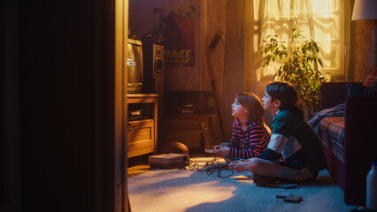Fototapeta na wymiar Nostalgic Childhood Concept: Young Brother and Sister Playing Old-School Arcade Video Game on Retro TV Set in a Living Room with Period-Correct Interior. Friends Spend the Day at Home Playing Games.