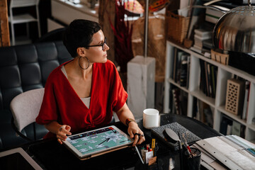 Fototapeta na wymiar Woman interior designer working with tablet at cozy workshop