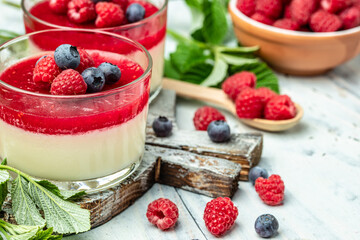 Italian dessert. Raspberry Panna cotta with raspberry jelly on a light background. Berry dessert with cream sauce in small jars. Long banner format. place for text