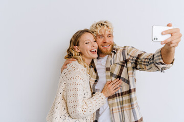 Young couple taking selfie while standing isolated