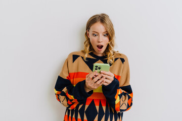 Shocked young woman using smartphone isolated over white background