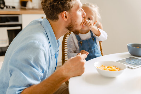 Young white father and his little daughter having breakfast and using tablet computer at home