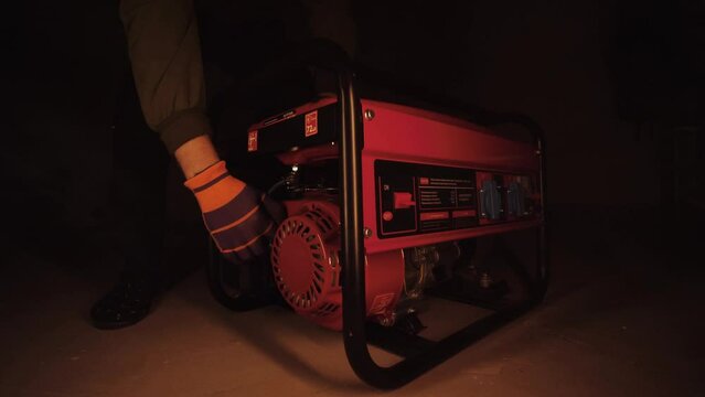 Man starts a gasoline generator of electricity.