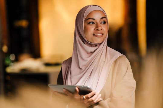 Arabian woman working on tablet while standing indoors