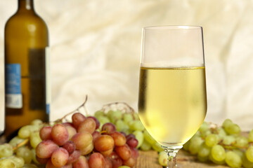 glass of wine with grapes on wooden table