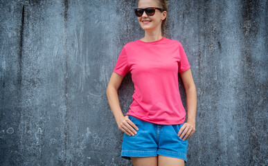 Female model wearing pink blank t-shirt on the background of an gray scratched wall.