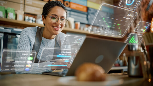 Beautiful Latina Coffee Shop Owner is Working on Laptop Computer and Checking Inventory in Cozy Cafe. Restaurant Manager Browsing Internet and Chatting with Friends. VFX Augmented Reality Concept.