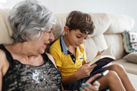 grandmother and grandson on the sofa at home enjoy reading for a while