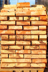 Orange brick stacked on a wooden pallet. Vertical image.